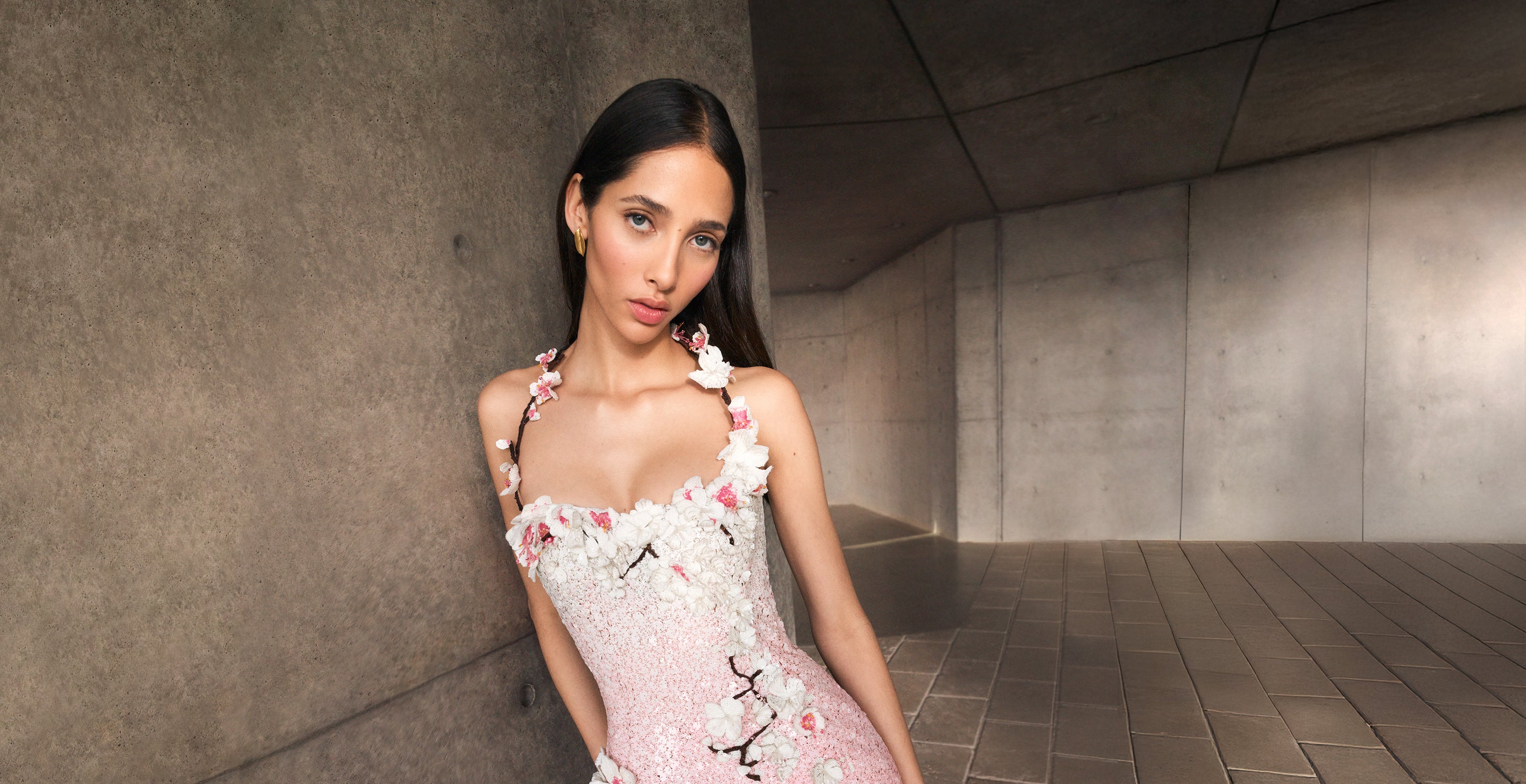 A model poses indoors in an embroidered Oscar de la Renta cocktail dress from the Pre-Fall 2025 collection. 