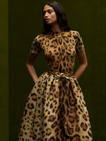 The model is wearing a jaguar-printed midi skirt and jaguar-printed mock neck short sleeve shirt. 