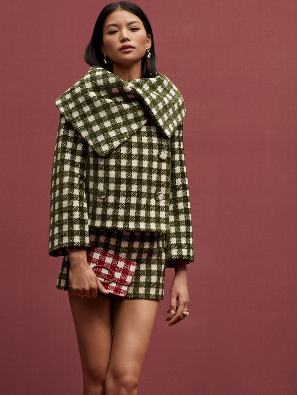 This model is in a matching green and white checkered tweed jacket and skirt with a red and white checkered bag. 