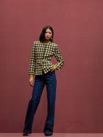 This model is wearing a green & white checked tweed jacket with a ginger satin blouse underneath and denim pants. 