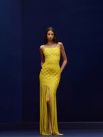 The model is wearing a woven yellow strapless dress with fringe in the bottom.