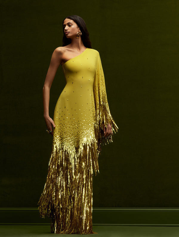 The model is wearing a one-shoulder silhouette cut in stretch silk georgette in a lively shade of ginger with dramatic, cascading sequin fringe from Oscar de la Renta's Fall 2024 Collection.