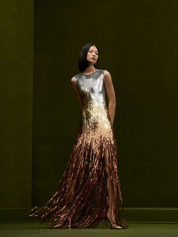 The model is wearing an ombre sequins sleeveless maxi dress that fades into fringe.