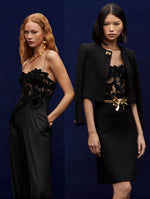 Two models pose together. The model in the left is wearing a black jumpsuit with peony velvet guipure too. The model in the left is wearing a peony velvet guipure corset, with a black tweed jacket and midi skirt.