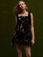 The model wears a black peony velvet guipure mini dress with velvet straps