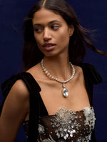 Close up of model wearing a dandelion embroidered dress with black velvet straps, paired with a crystal necklace. Zoom view