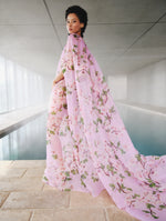 A model poses in front of an indoor pool in an Oscar de la Renta floral caftan from the Pre-Fall 2025 collection.