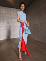 A model poses indoors in a blue and red cocktail dress from Oscar de la Renta’s Pre-Fall 2025 collection. 