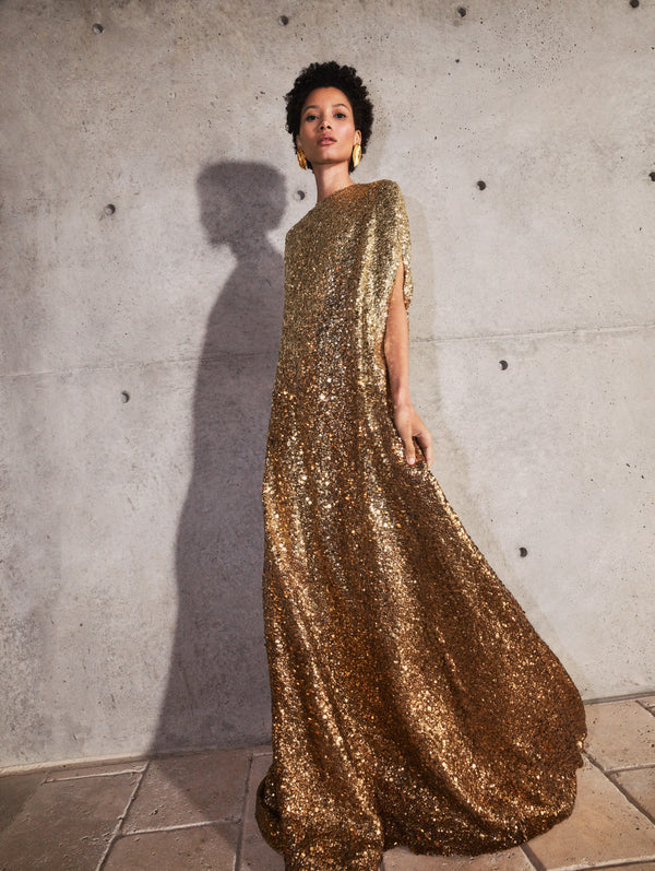 A model poses indoors in a metallic caftan from Oscar de la Renta’s Pre-Fall 2025 collection. 