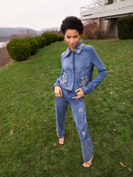 A model poses outside in a blue suede jacket and pant set from Oscar de la Renta’s Pre-Fall 2025 collection. 