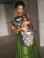 A model poses indoors with two Oscar de la Renta bucket bags from their Pre-Fall 2025 collection. 