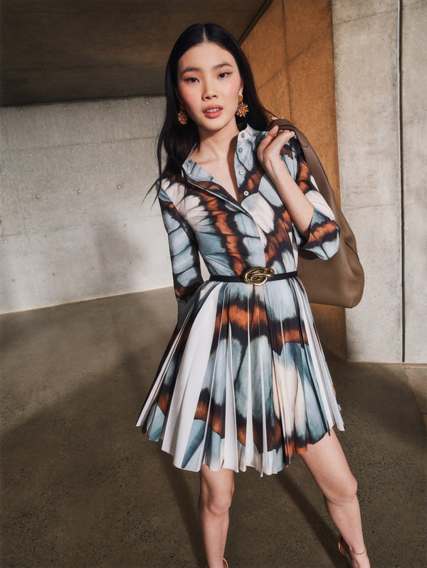 A model poses indoors in a blue and brown butterfly printed mini dress from Oscar de la Renta’s Pre-Fall 2025 collection. 