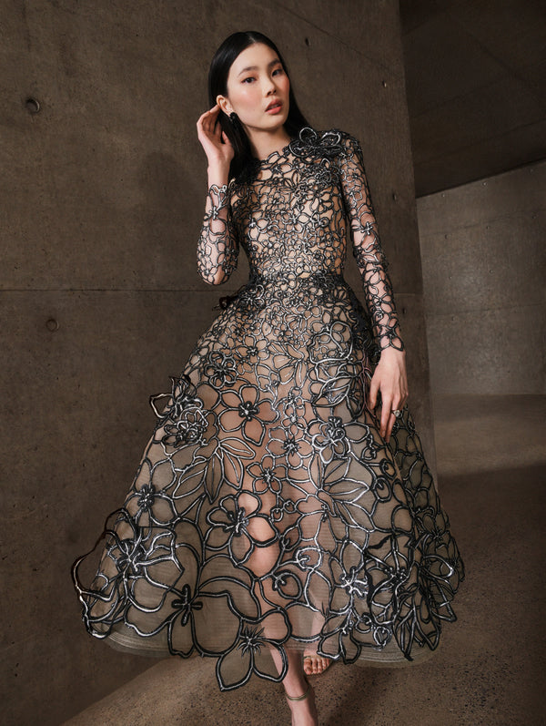 A model poses indoors in an embroidered cocktail dress from Oscar de la Renta’s Pre-Fall 2025 collection. 