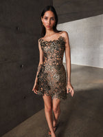 A model poses indoors in an embroidered cocktail dress from Oscar de la Renta’s Pre-Fall 2025 collection. 