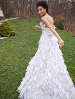 A model poses outside in a white feather strapless gown from Oscar de la Renta’s Pre-Fall 2025 collection. 