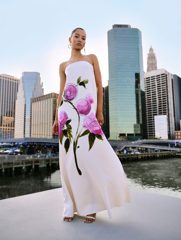 The model poses in a white strapless gown with an abstract English Rose hand painted by Co-Creative Director Fernando Garcia from Oscar de la Renta's Spring 2025 collection against the New York City skyline. 