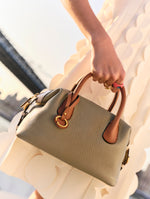 The model is carrying the new grey and brown colorway of the Mini Dahlia handbag. 