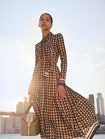 The model is wearing a long sleeve high neck dress with a brown and black geometric pattern. 