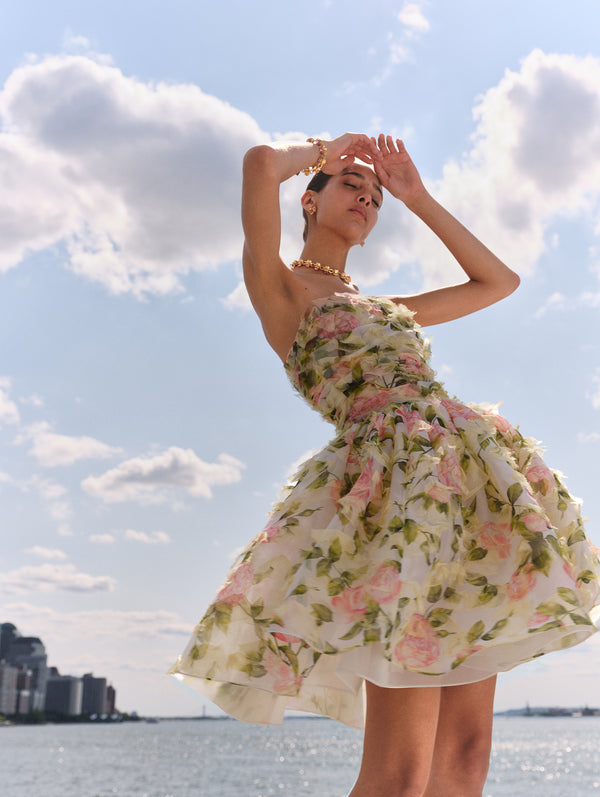 The model wears a strapless mini dress adorned with pink english roses from Oscar de la Renta's Spring 2025 Collection. 